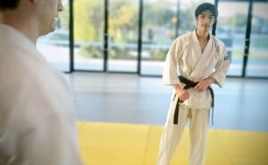 A man in karate uniform adjusting his black belt
